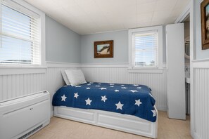 A bedroom with a bed, white walls, a window, and a painting. - Cape Shore Oceanfront—Beach & Creek Views (East Sandwich)