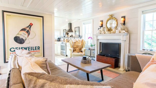 A living room with a sofa, a coffee table, a fireplace, and a kitchen in the background.