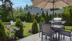 A deck with outdoor furniture, a grill, and a large umbrella.