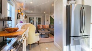 A kitchen with a stainless steel refrigerator, wooden countertop, and a dining area with a sofa and table.