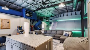 A modern living room with a kitchen area, a sofa, and a gaming console. - Hangar 18 @ Area 51 | Themed | Pet Friendly (Hurricane)