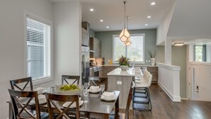 Una cocina moderna con comedor, que cuenta con una isla central, iluminación empotrada y vistas al espacio de estar contiguo.