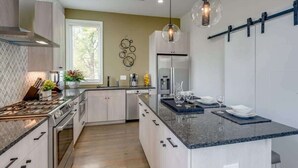 Una cocina moderna con una isla central, electrodomésticos de acero inoxidable e iluminación colgante.
