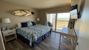 A bedroom with a bed, a desk, a TV, and a surfboard on the wall.