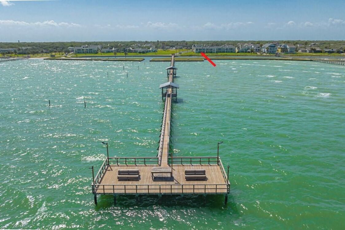 A pier extending into a body of water with a row of benches and a small structure at the end.