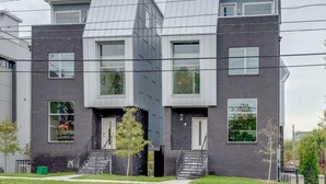 Une maison moderne à deux étages, dotée d’un toit plat, de grandes fenêtres et d’une porte d’entrée bien visible.