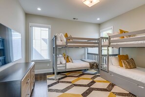 Ein Zimmer mit Etagenbetten, einem Schreibtisch und einem Fenster mit Jalousien.