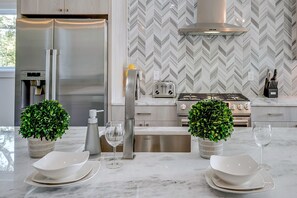 A modern kitchen with a stainless steel refrigerator, a built-in water dispenser, a gas stove, and a herringbone-patterned backsplash. - Group Getaway | Walkable Gulch Location + Parking! (Nashville)