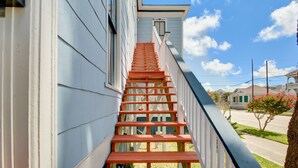 Un escalier menant à une maison, avec un ciel bleu clair en arrière-plan.