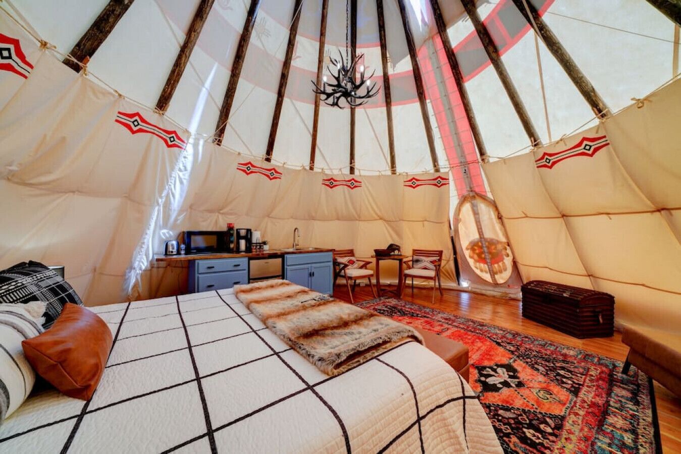 Un interior acogedor de una tienda de campaña con una cama, una kitchenette pequeña y un comedor.