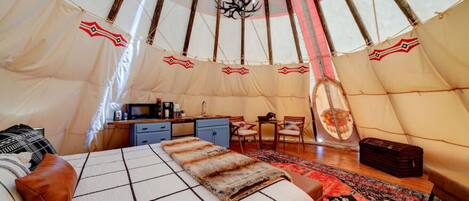 Un interior acogedor de una tienda de campaña con una cama, una kitchenette pequeña y un comedor.