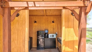 A wooden structure with a built-in kitchen area, including a refrigerator, microwave, and coffee maker.