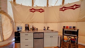 Una cocina compacta con lavamanos, cafetera y microondas.