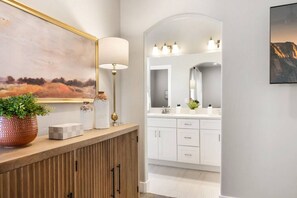 Un baño moderno con tocador de madera, un espejo grande y un cuadro sobre el espejo.