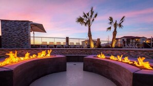 An outdoor seating area with fire pits and lounge chairs, surrounded by palm trees and a stone wall. - 6 Bed 6 Bath Sleeps 22 w/4 Private Master Suites! (Hurricane)