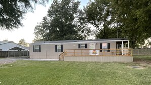 A mobile home with a covered porch and a small deck.