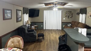 A living room with a sofa, a chair, a coffee table, a TV, and a ceiling fan.