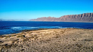 Paisagem costeira com praia, falésias rochosas e o oceano.