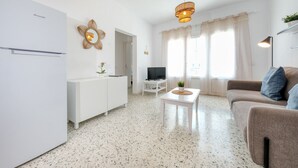Uma sala de estar moderna com um sofá branco, uma mesa de centro e uma televisão.