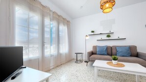 Uma sala de estar moderna com um sofá, uma mesa de centro, uma televisão e um abajur.