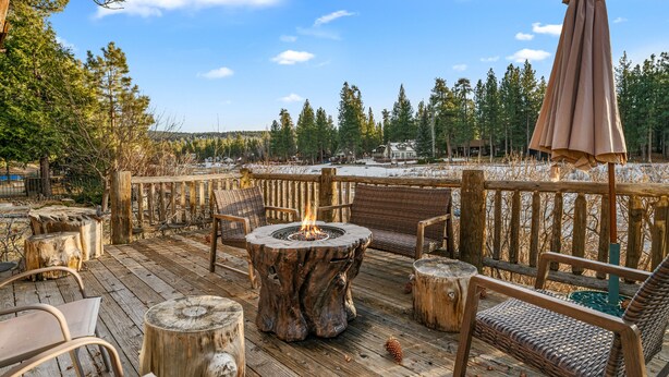 Eine Holzterrasse mit Feuerstelle, Korbmöbeln und Blick auf eine verschneite Landschaft.