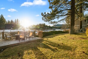 Una terraza con mobiliario exterior, una chimenea y vistas a un lago y montañas.