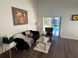 Relax in this stylish living room with a sofa, side table, and potted plant, plus a coffee table and framed artwork.