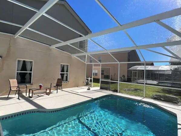 Relax by the pool surrounded by a shaded structure and adjacent to a building.