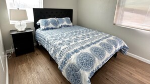 A bedroom with a bed, a nightstand, a lamp, and a window with blinds. - A Beautiful Storey - Quiet Condo minutes from Midland Memorial (MIDLAND)