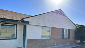 A single-story house with a brick facade and white siding, featuring a front door, two windows with shutters, and a small front yard. - A Beautiful Storey - Quiet Condo minutes from Midland Memorial (MIDLAND)