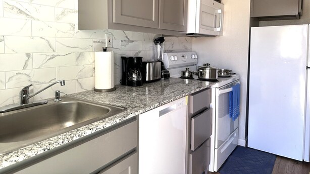 A modern kitchen with granite countertops, stainless steel appliances, and marble backsplash. - A Beautiful Storey - Quiet Condo minutes from Midland Memorial (MIDLAND)