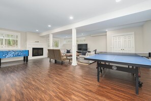 Relax in this inviting living area with a ping pong table, sofa, and chair, featuring a flat-screen TV and a fireplace.