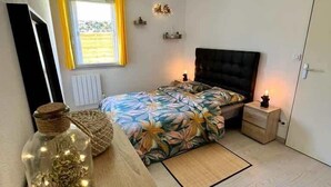 Un dormitorio con cama, mesita de noche, lámpara y un frasco decorativo en una cómoda.