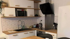 Una cocina moderna con armarios blancos, una mesa de comedor de madera y sillas negras.