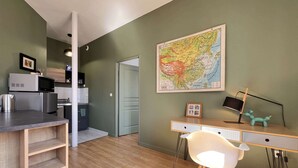 Cocina moderna con microondas, hervidor, y armarios, un escritorio de madera con computadora y silla, y un mapa en la pared.