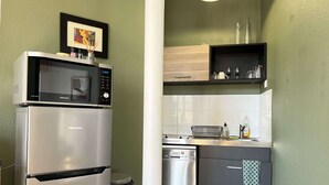 Una cocina compacta con refrigerador de acero inoxidable, microondas, lavavajillas y estufa.
