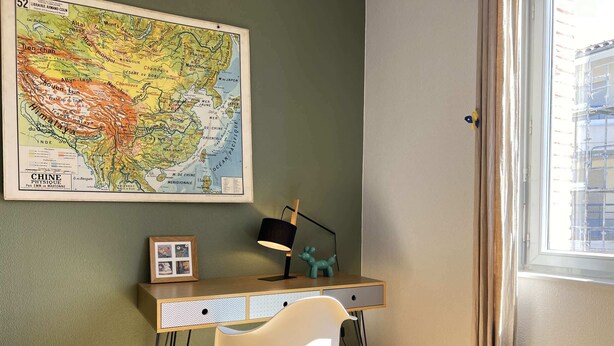 Un espacio de trabajo con escritorio, silla, lámpara y un mapa de China en la pared.