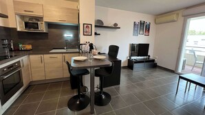 Una cocina moderna con comedor, que incluye un microondas, estufa y una mesa de comedor con sillas.