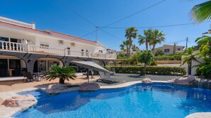 A swimming pool with a stone border, palm trees, and a building with a balcony. - CostaBlancaDreams - Villa Sardonyx in Calpe (Calpe / Calp)