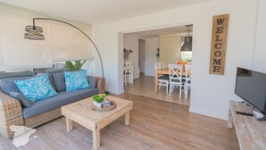 A modern living room with a sofa, coffee table, and a TV. There is a dining area with chairs and a table. A 'WELCOME' sign is on the wall. - CostaBlancaDreams - Villa Sardonyx in Calpe (Calpe / Calp)