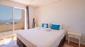 Une chambre avec un grand lit, une table de chevet et une vue sur la mer.