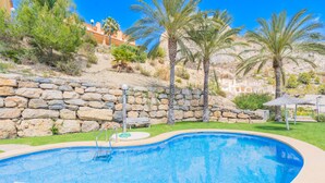 Une piscine avec un mur en pierre et des palmiers en arrière-plan.