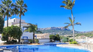 A swimming pool with a view of mountains, palm trees, and a building with a white facade. - CostaBlancaDreams - Casanova in Calpe (Calpe / Calp)