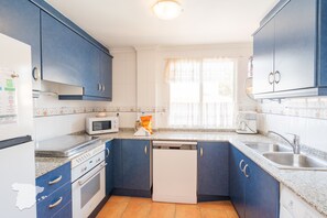 A kitchen with blue cabinets, a microwave, a stove, a dishwasher, and a sink.
