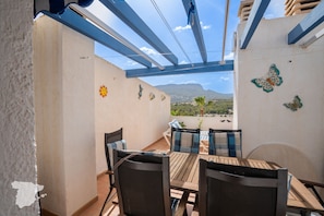 A patio with a table and chairs, a view of the landscape, and decorative wall art.