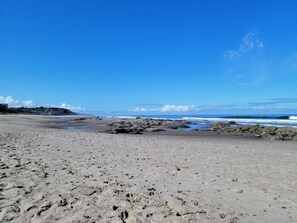 Een strand met rotsachtige delen en een heldere lucht.