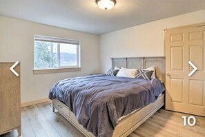 Een slaapkamer met een bed, een raam, een deur en een houten vloer.
