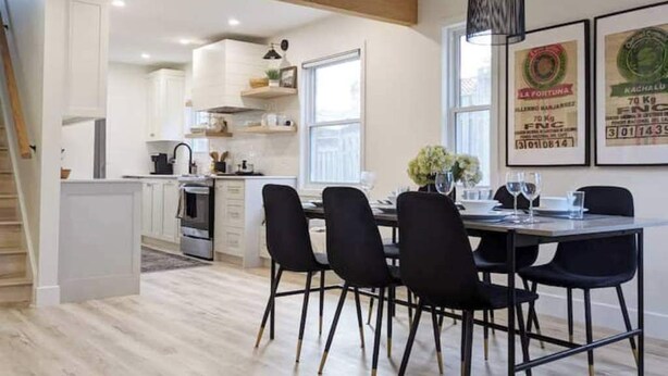 A modern kitchen with white cabinets, a dining area with black chairs, and a staircase leading to another level. - Perfect for large groups, lots of parking, 5BRs, Game Room, Fast Wifi (Kitchener)