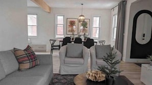 A modern living room with a grey sofa, a round coffee table, and a dining area in the background. - Perfect for large groups, lots of parking, 5BRs, Game Room, Fast Wifi (Kitchener)