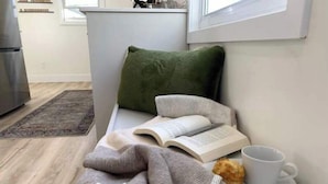 A cozy reading nook with a sofa, a book, a cup, and a pastry. - Perfect for large groups, lots of parking, 5BRs, Game Room, Fast Wifi (Kitchener)